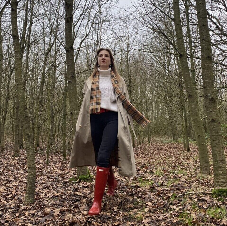 woman walking thorough forest in red hunter rain boots, a chunky knit sweater and a burberrys trench coat | Ode2style.com