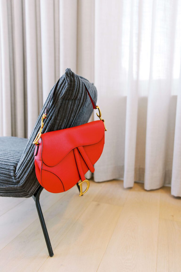 red Dior Saddle bag hanging from chair | Ode2style.com