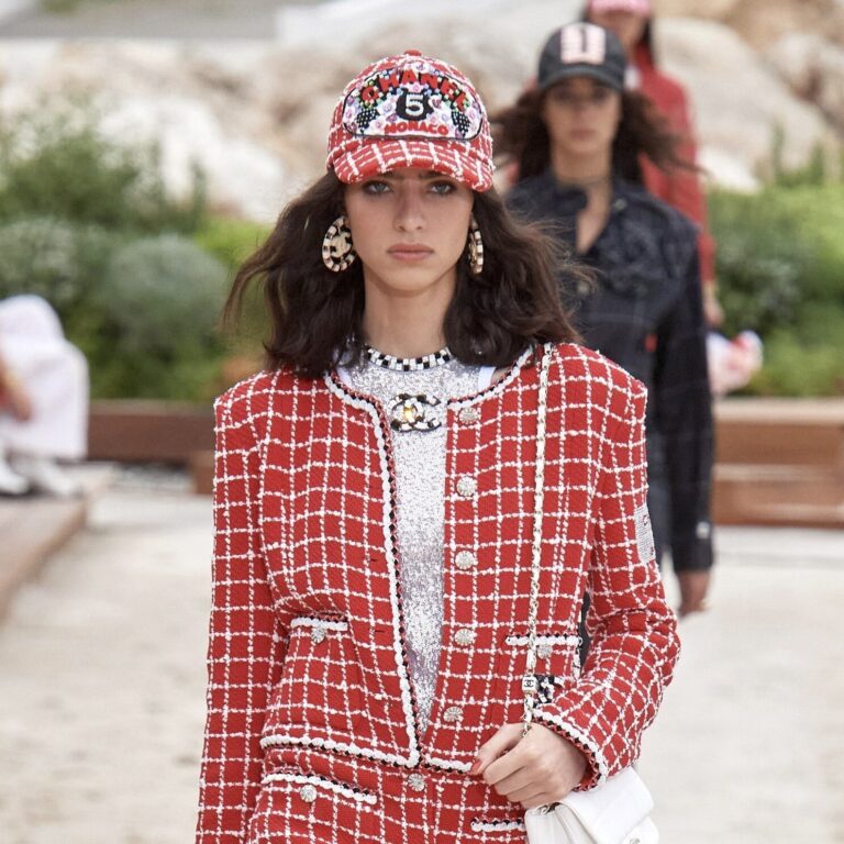 Woman in a red and white tweed chanel suit and cap at the 2023 cruise show | Ode2style.com