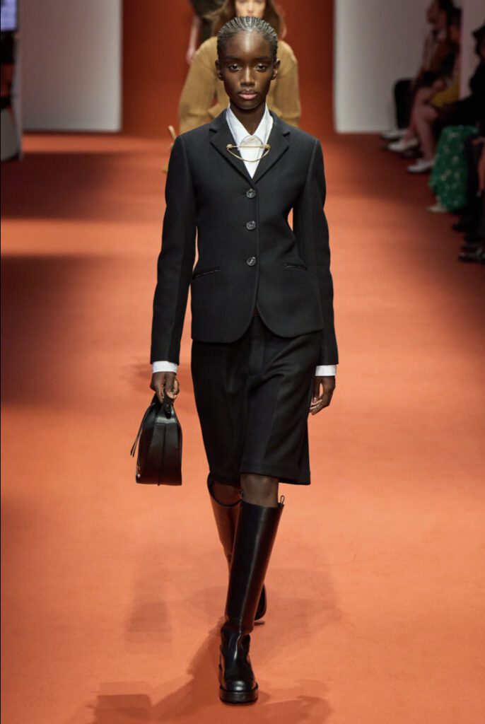 Woman wearing Black suit with shorts and tall black boots at the Tod's fashion show SS23 | Ode2style.com
