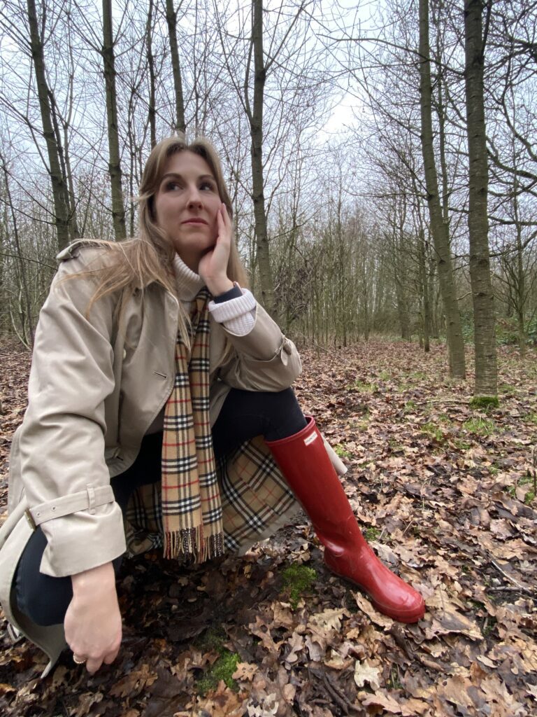 Astrid wearing a burberrys trenchcoat, white knitted sweater and red Hunter boots in a forest | Ode2style.com