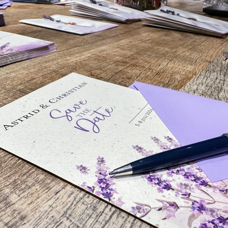 Lavender inspired wedding save the date on a table with a lilac envelope and a pen